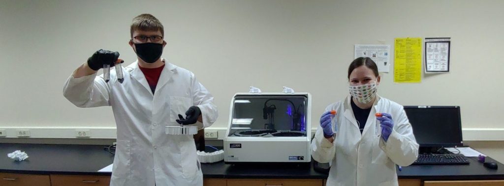 UW-Green Bay students hold the test tubes they use to analyze materials.