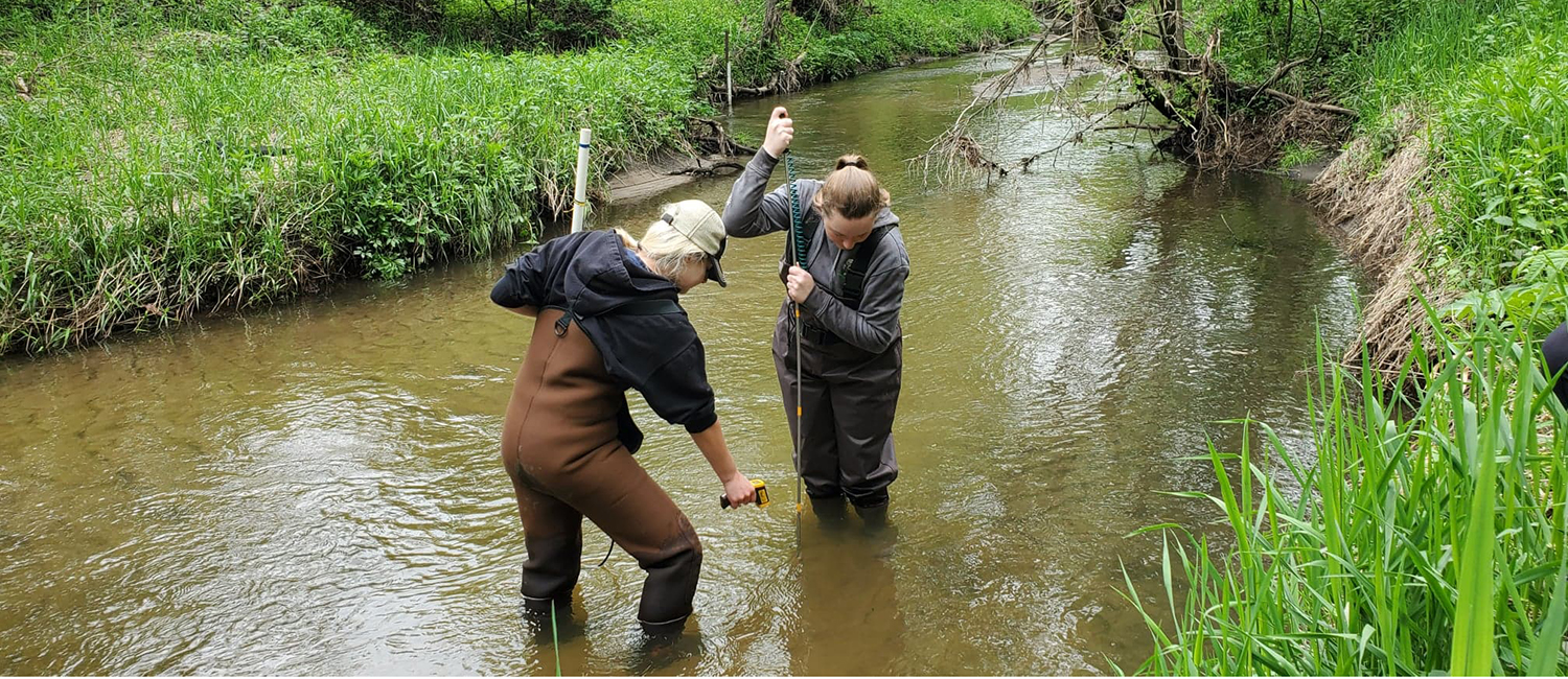 students measuring water in river